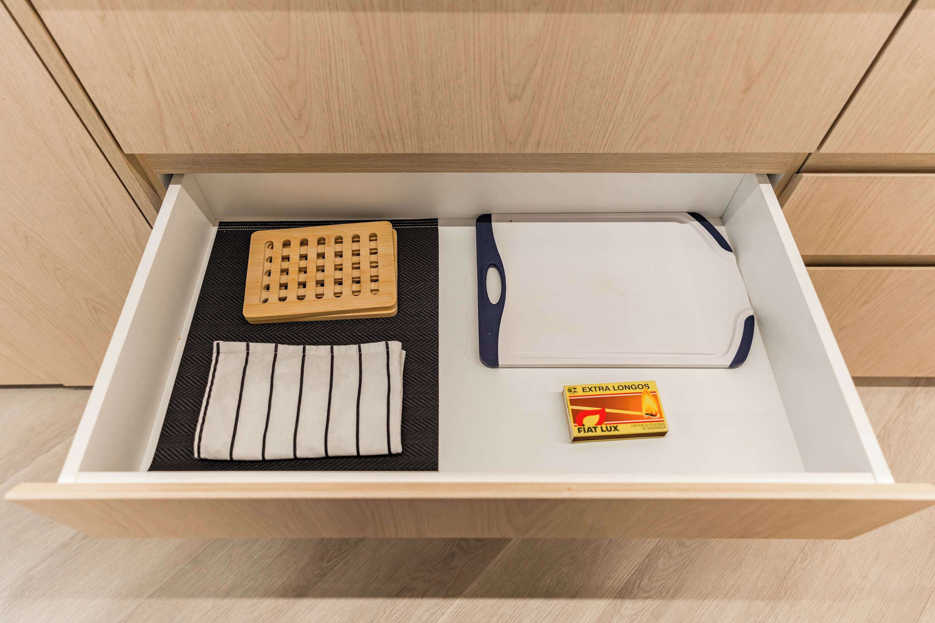 A drawer with a cutting board, a knife, a cloth, and a box of FIAT LUX tissues.