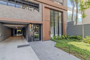 A modern building with a covered entrance, a glass door, and a small garden area. - #AT32 | Cyclinn Itaim Jesuino (Itaim Bibi)