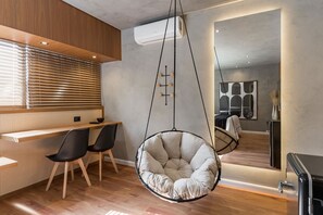 Ein modernes Interieur mit einem Hängekorbstuhl, einem Holztisch und einem Spiegel, der den Raum wiedergibt.