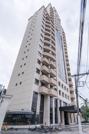 Ein hohes, modernes Gebäude mit einer geschwungenen Fassade, großen Fenstern und einem überdachten Eingangsbereich.