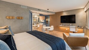 Una habitación de hotel moderna con una cama grande, un escritorio, un televisor y una zona de estar.