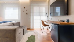 A modern living room with a sofa, a desk, a chair, and a large mirror. - #IN607 | Cyclinn Jesuíno Arruda Itaim (Itaim Bibi)