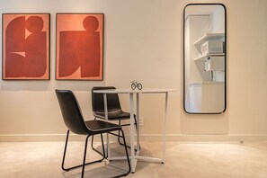 A modern room with a white table, two black chairs, a large mirror, and abstract art on the wall. - #WP302 | Cyclinn Paulista Jardins (Jardim Paulista)