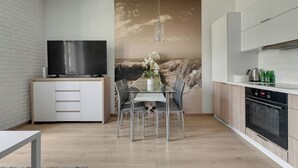 A modern kitchen with a dining area, a TV, and a stone wall backdrop. - Nadmorski Zakątek by Grand Apartments (Sopot)