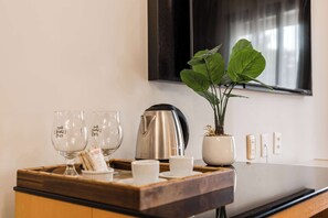 A kitchen counter with a tray holding wine glasses, a coffee pot, and a potted plant. - Flat a 5min da Faria Lima | IN208 (Itaim Bibi)