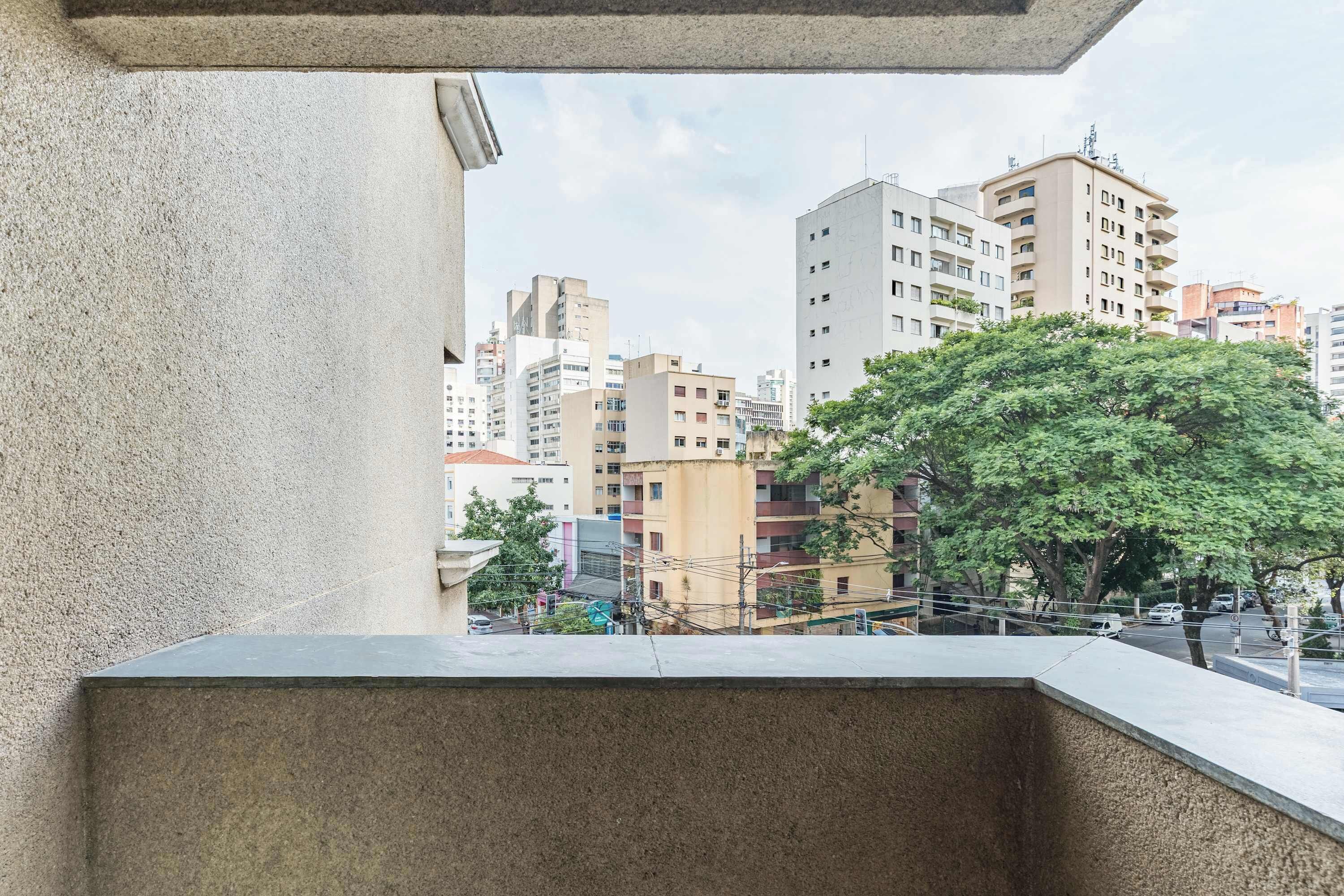 Ein Balkon mit Blick auf eine Stadtansicht, einschließlich Gebäude und eines Baumes.