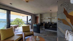 Una sala de estar moderna con un sofá, una mesa de centro y vistas a un balcón con zona de comedor.