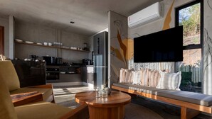 Una sala moderna con un sofá, una mesa de centro y una zona de cocina con electrodomésticos.