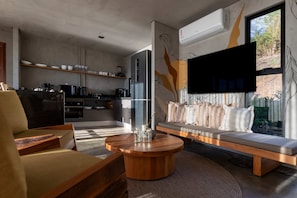 A modern living room with a sofa, a coffee table, and a kitchen area with appliances.