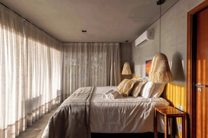 Une chambre à coucher avec un lit, des rideaux, une lampe suspendue et une table de chevet en bois.