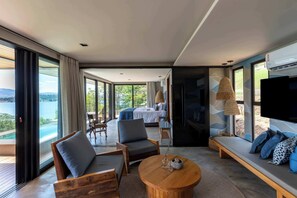 Una habitación moderna con una cama grande, un televisor y una zona de estar con vistas al exterior.