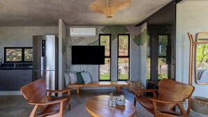 Una cocina moderna con refrigerador integrado, televisor de pantalla plana y comedor con sillas de madera y una mesa redonda.