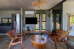 Una cocina moderna con refrigerador integrado, televisor de pantalla plana y comedor con sillas de madera y una mesa redonda.