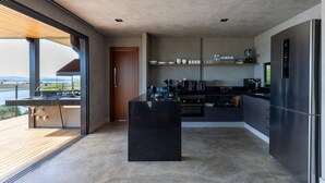 Eine moderne Küche mit einer großen Kochinsel, integrierten Geräten und Blick ins Freie.