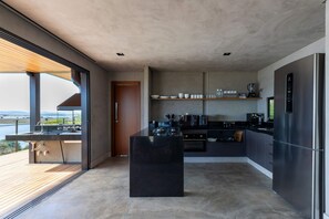 Una cocina moderna con una isla grande, electrodomésticos integrados y vistas al exterior.