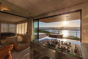Una sala de estar moderna con una mesa de comedor de vidrio, un sofá de cuero y vista al océano.