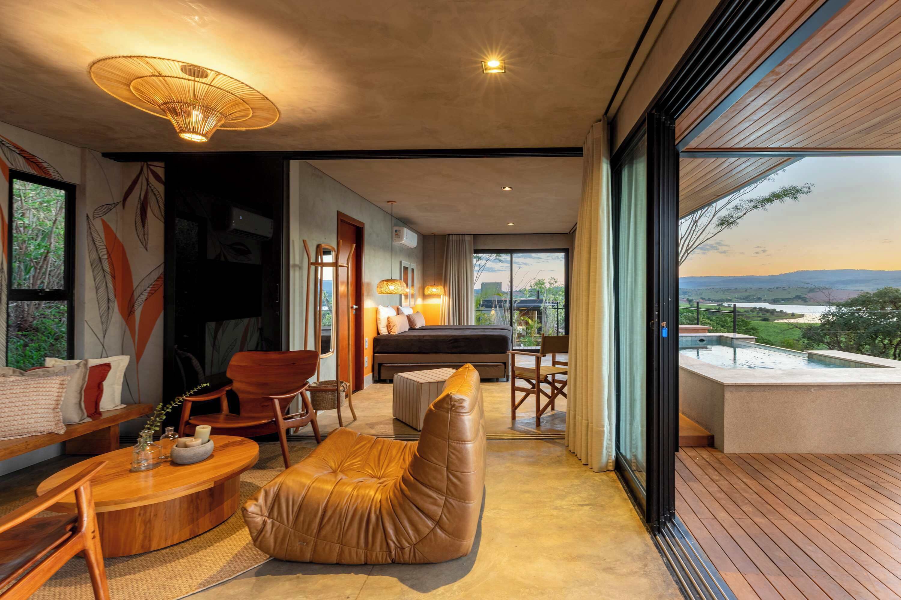 A modern living room with a sofa, chairs, a coffee table, a piano, and a view of a hot tub and landscape.