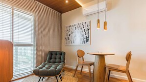 Een moderne woonkamer met een fauteuil, een ronde houten tafel en een kunstwerk aan de muur.
