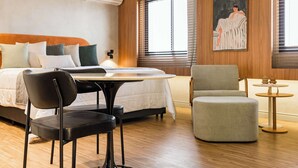 Une chambre d’hôtel avec un lit, une table, une chaise et une petite table d’appoint.