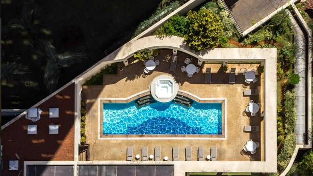Vue aérienne d’un espace piscine sur un toit, avec une piscine, des chaises longues et un panneau indiquant le chiffre « 5 ».