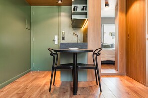 A small dining area with a table and two chairs, a green door, and a wooden floor. - #BE902 | Cyclinn Vila Olímpia Berrini (Berrini)