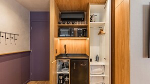 Eine kleine Küche mit Mikrowelle, Kaffeemaschine und Kühlschrank.