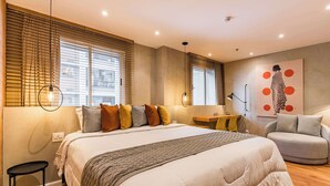 A bedroom with a large bed, a desk, a chair, and a wall with a geometric artwork. - #WP211 | Cyclinn Paulista Jardins (Jardim Paulista)