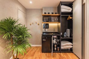 A compact kitchen with a refrigerator, microwave, and coffee maker, a small sink, and a plant. - #WP211 | Cyclinn Paulista Jardins (Jardim Paulista)