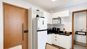 A compact kitchen with a refrigerator, microwave, coffee maker, and a small sink. - Flat Miray Exclusive com Piscina (Tamandaré)