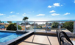 A rooftop pool area with a clear view of the ocean and surrounding buildings.
