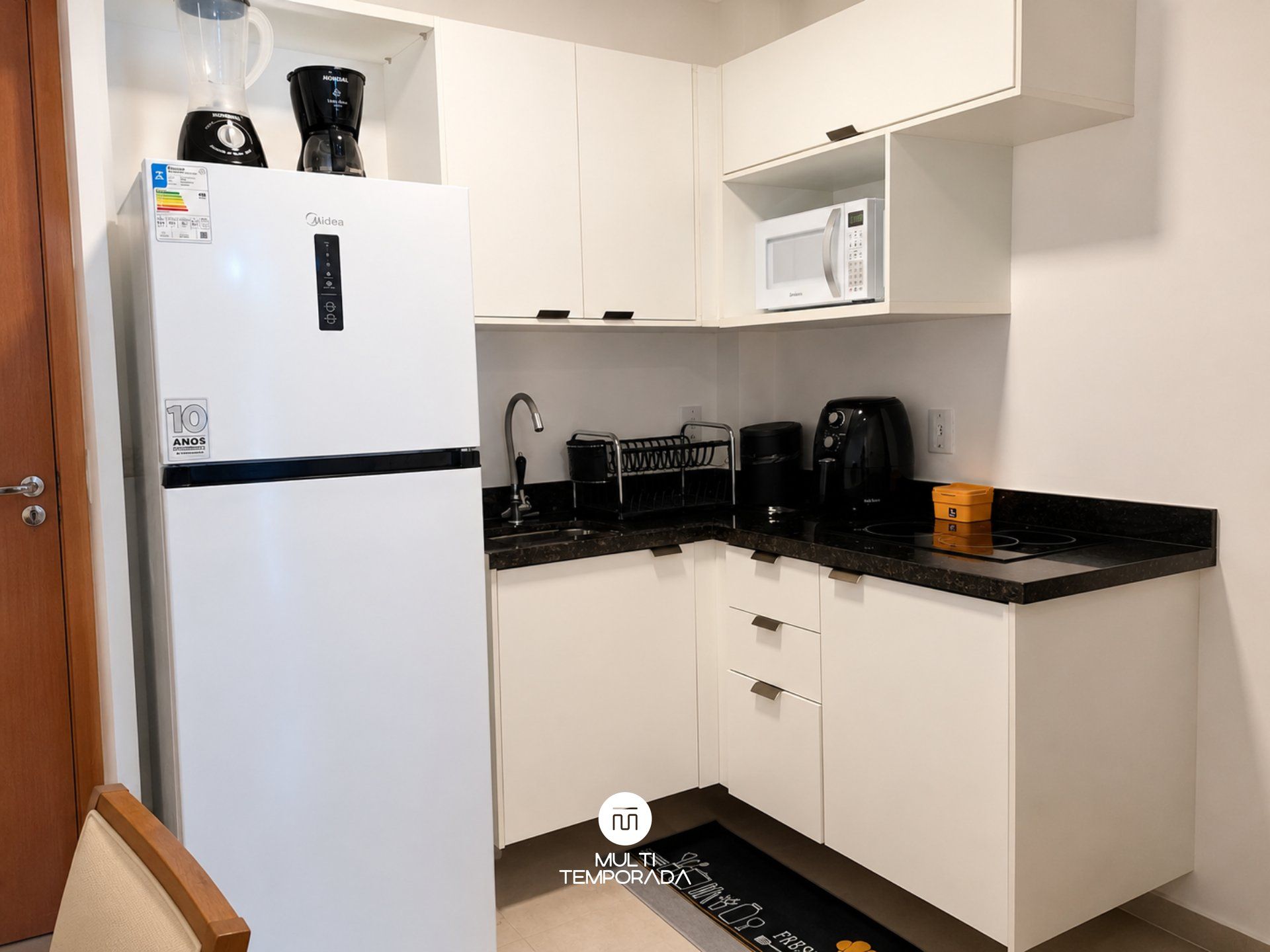 Eine kleine Küche mit einem weißen Kühlschrank, einer Mikrowelle, einer Kaffeemaschine und einem Toaster.