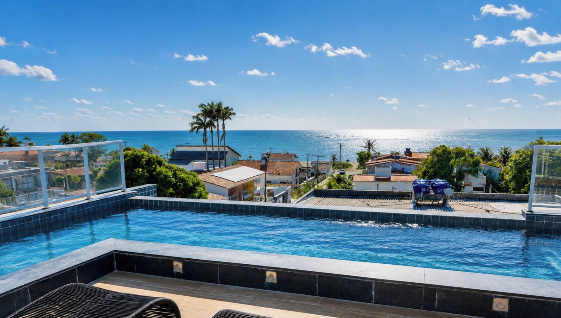 A swimming pool with a view of the ocean and buildings in the background.