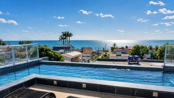 A swimming pool with a view of the ocean and buildings in the background.