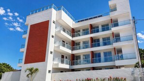 A multi-story building with balconies, a flat roof, and a clear sky. - Flat Miray Exclusive com Piscina (Tamandaré)