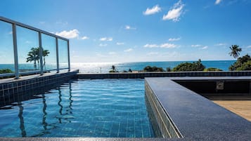 A swimming pool with a view of the ocean and palm trees.