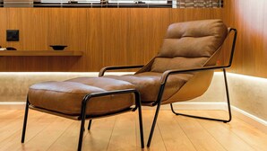 A brown leather chair with metal frame legs, a wooden wall, and a wooden floor. - Cyclinn a 400m do WTC Berrini Vila Olímpia #WB1101 (Berrini)