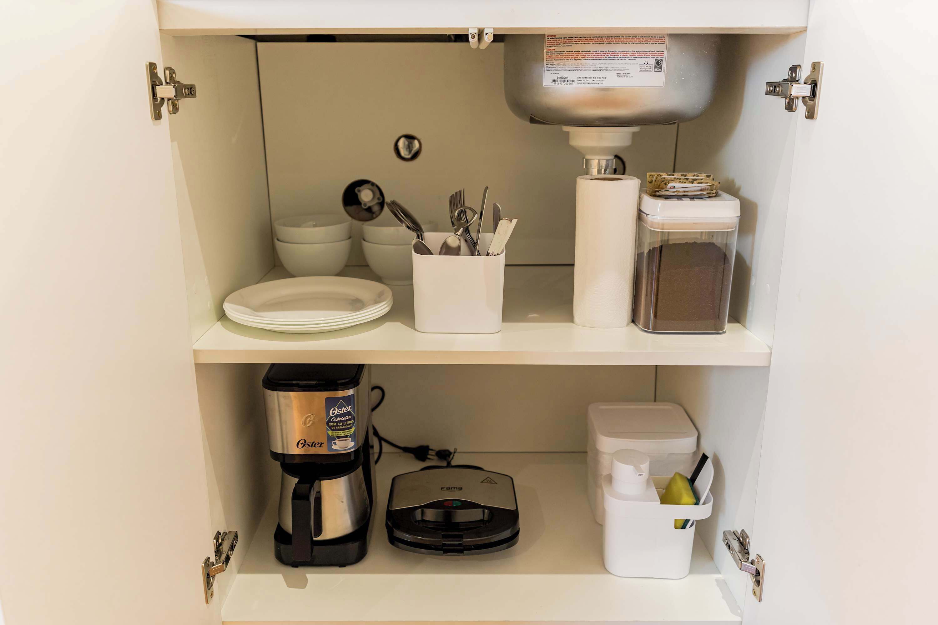 Eine Küche mit Kaffeemaschine, Lebensmittelschneider und Mülleimer.