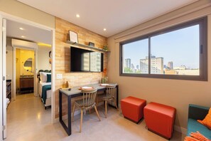 A modern hotel room with a dining area, a city view, and a separate living space. - Studio Completo a 500m do Metrô Borba Gato | AD503 (Brooklin)