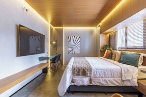 Ein modernes Schlafzimmer mit Bett, Schreibtisch und Kunstwerken an den Wänden.