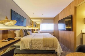 Ein modernes Hotelzimmer mit einem großen Bett, Nachttischen, einem Schreibtisch, einem Flachbildfernseher und einem großen Fenster.