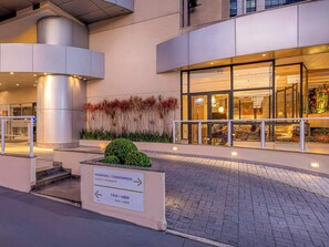 Ein moderner Hotel Eingang mit einem Schild, das die Wegweisung zu Hotelzimmern und Taxi-/Uber-Diensten zeigt.