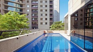 Una piscina con vistas despejadas a edificios altos cercanos y zonas verdes.