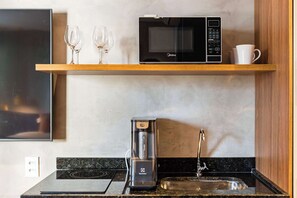 A kitchen with a microwave, coffee maker, and wine glasses on a shelf. - #NP904 | Cyclinn Pinheiros (Pinheiros)