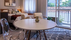 Una camera d'albergo moderna con un letto, un tavolo da pranzo, sedie, un divano e un balcone con vista.