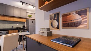 Una cucina moderna con mobili grigi, un piano di lavoro in legno, una zona pranzo con tavolo e sedie bianche e due quadri appesi al muro.