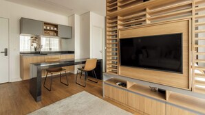 A modern kitchen with a built-in TV, wooden shelves, and a dining area with a chair. - #VN1609 | Cyclinn Vila Olímpia (Vila Olímpia)