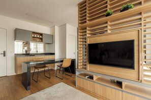 Eine moderne Küche mit integriertem Fernseher, Holzböden und einem Essbereich mit einem Stuhl.
