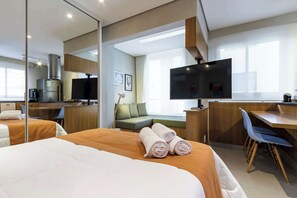 Ett hotellrum med en säng, ett skrivbord, en tv, en soffa och en matplats.
