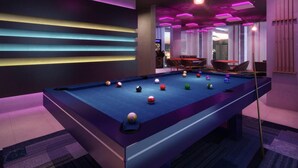 A pool table with balls, a seating area with chairs, and a view of the cityscape through large windows. - #CA405 | Cyclinn Casa do Ator Vila Olímpia (Vila Olímpia)