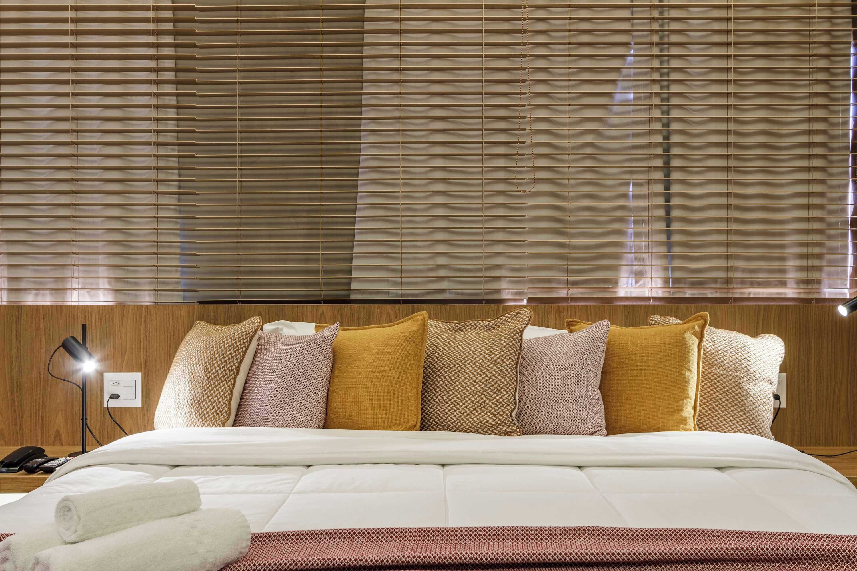 Ein Hotelzimmer mit Bett, Kissen, einer Nachttischlampe und einer Steckdose.